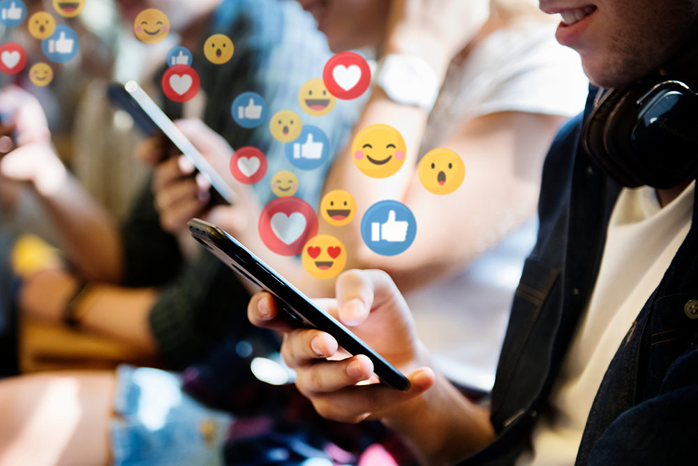 People sitting down on subway on smartphones with emojis around them