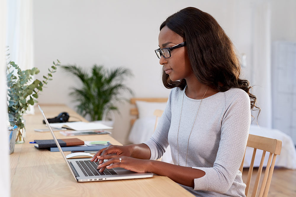 Woman sitting at table typing on laptop