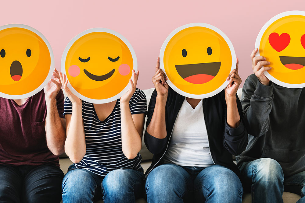 People sitting with emojis covering faces