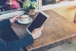 A woman scrolls through his tablet while sitting at a cafe.