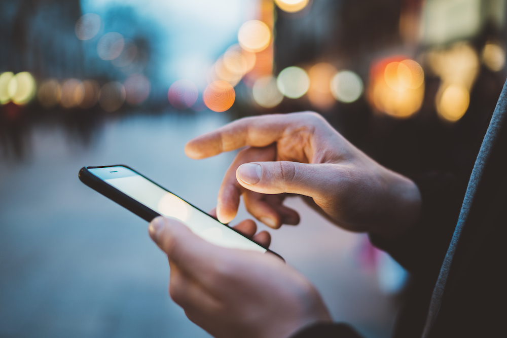 A man using a smart phone outdoors