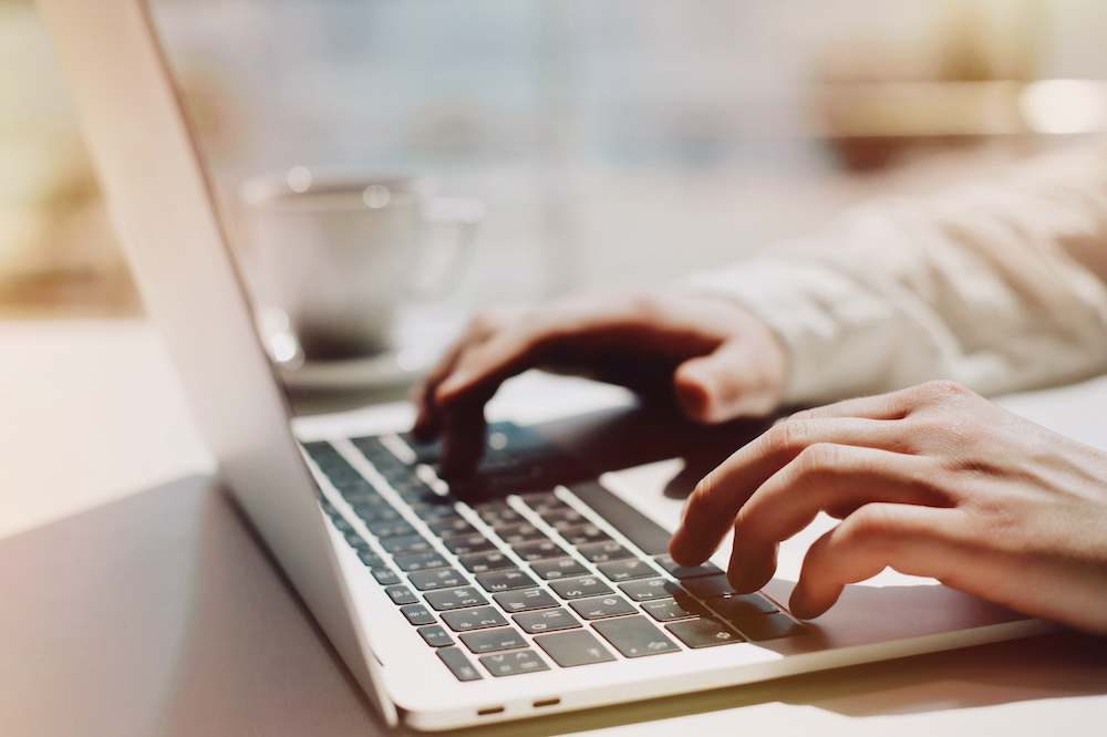 A businessman types on a blog while in a cafe