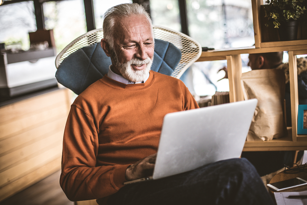 A senior man using a computer to research various senior living communities in the area