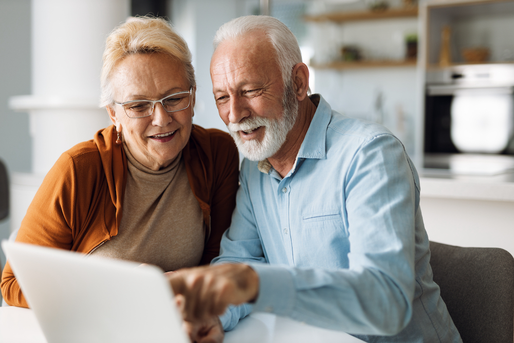 A happy senior couple using a computer at home