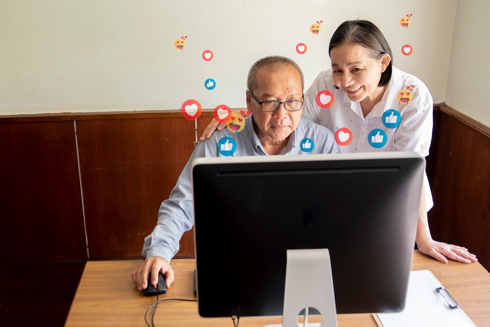 A senior couple using social media on their computer
