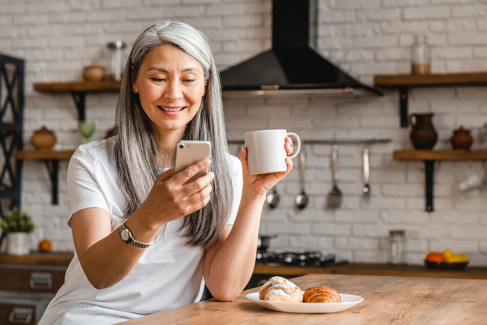 A happy older woman searching for senior living communities on her phone