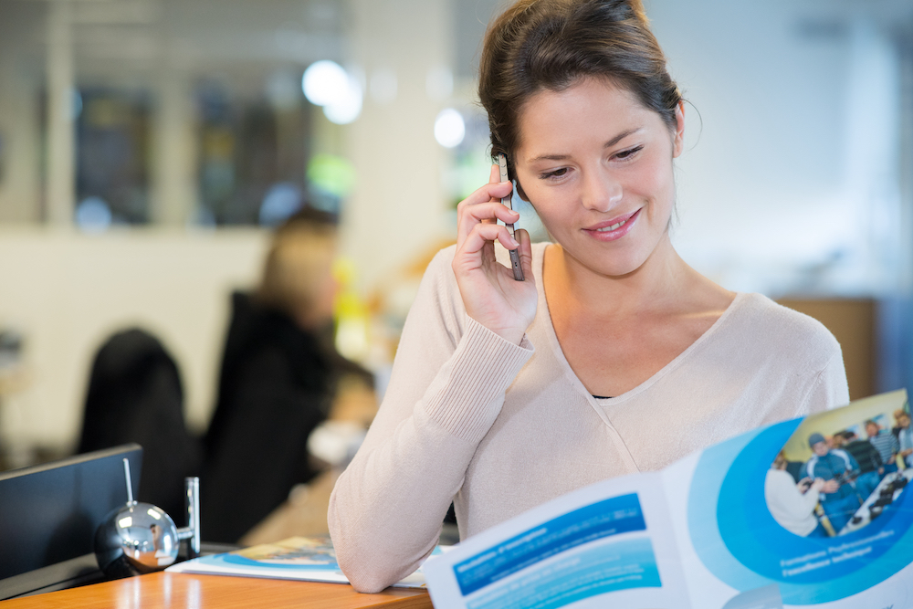 A woman talking on the phone while looking through print marketing options