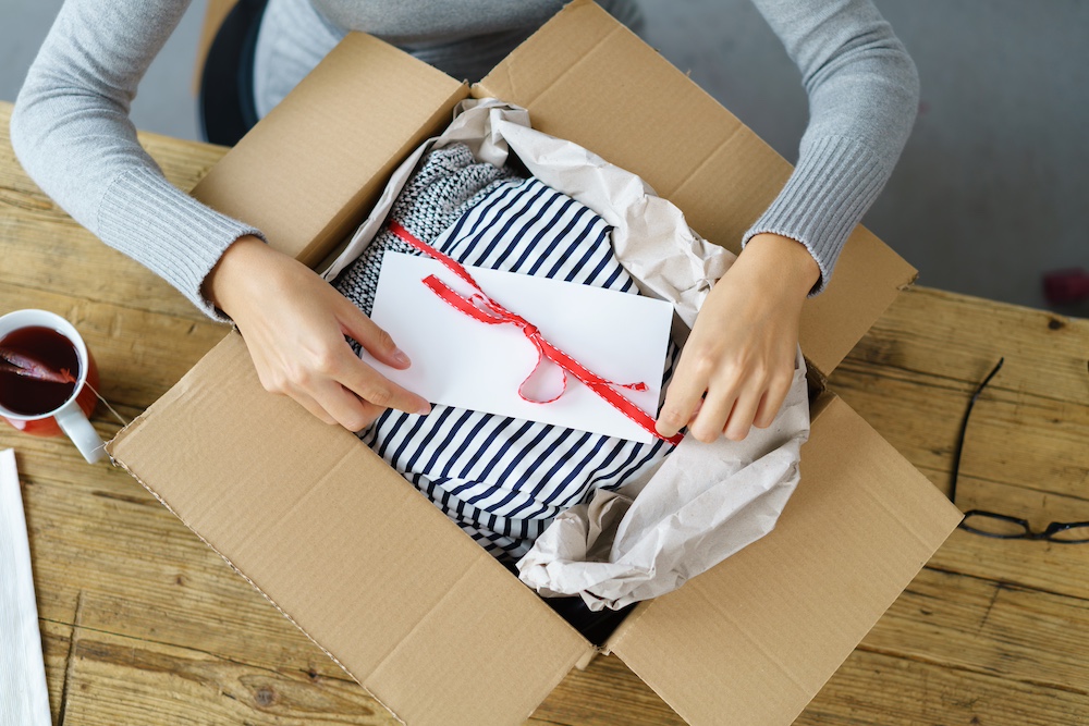 A woman opening up a holiday-themed box as a way of adding creative printing solutions to her business