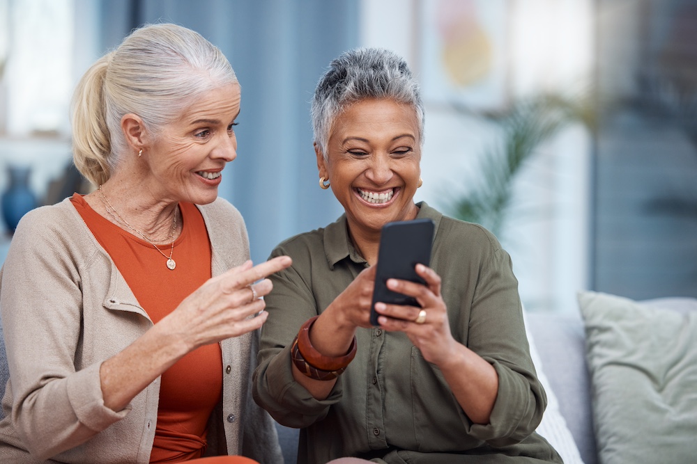 Two senior women using social media on their phone