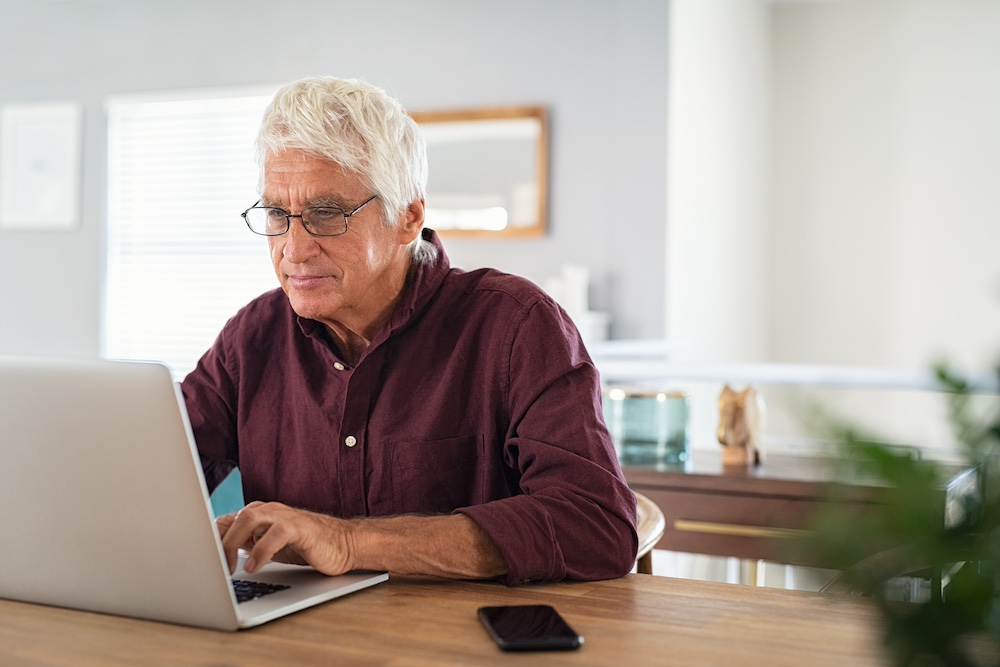 A senior man using a computer to check out assisted living marketing