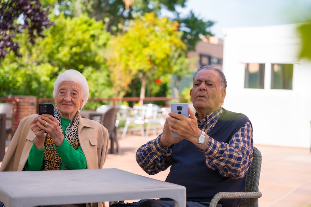 Two seniors outside looking at Assisted Living Website Design on phones